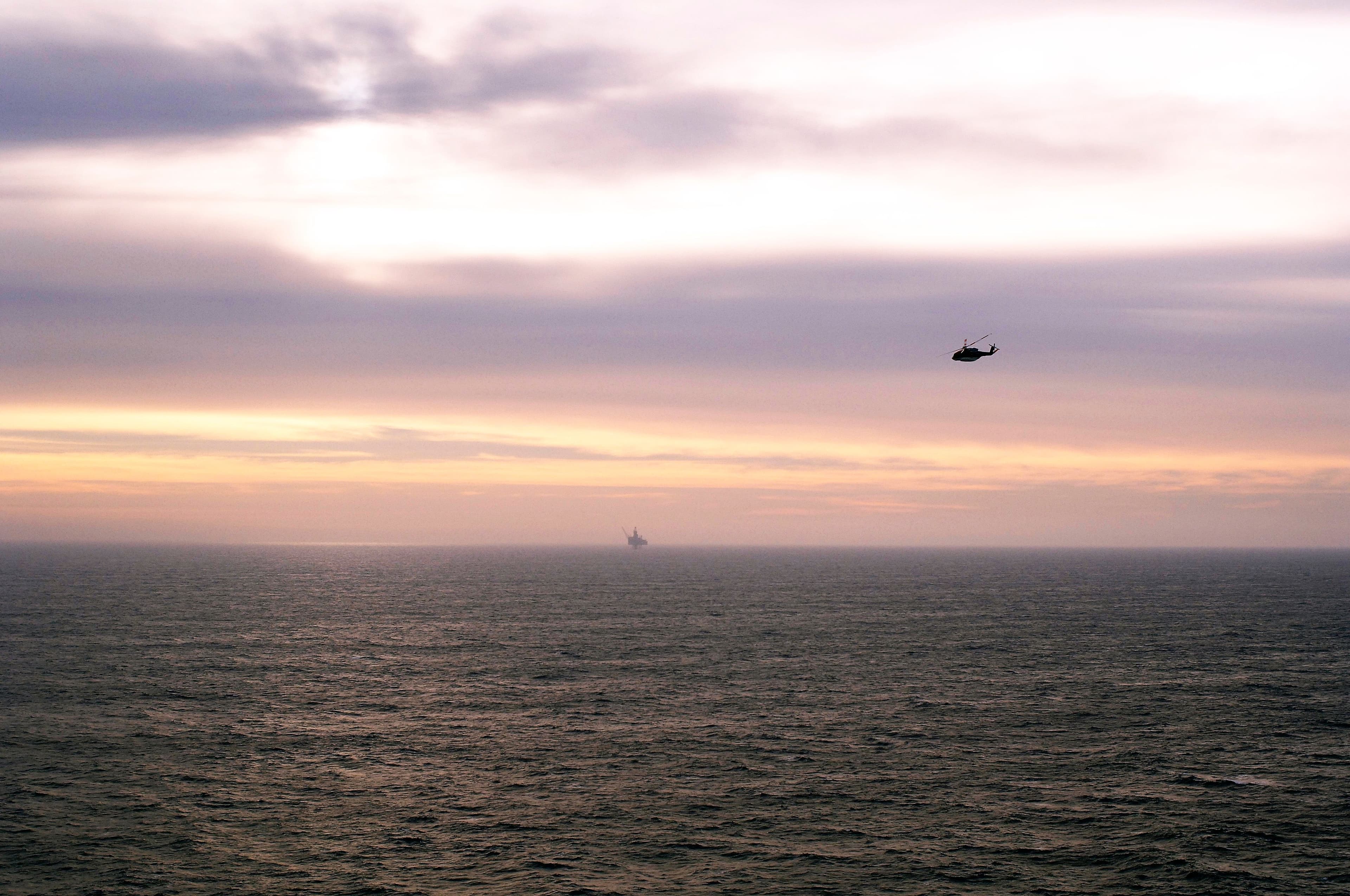 Bilde av en plattform i solnedgang og et helikopter